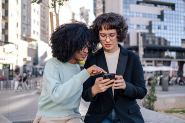 Two friends looking at smartphone in the street