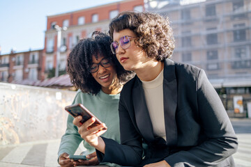 Two friends looking at smartphone in the street