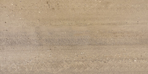 panorama of road from above on surface of gravel road with car tire tracks.