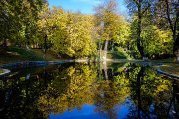 Landscape with many large green and yellow trees near the lake in Kiseleff Park in Bucharest,...