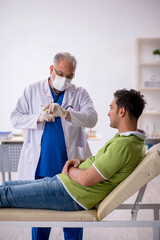 Obraz premium Young male patient visiting old male doctor in vaccination conce