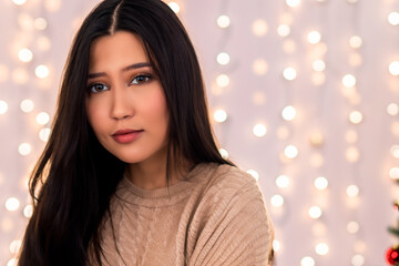 Christmas portrait of a beautiful brunette woman with brown eyes and a gray winter sweater