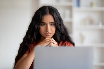 Focused young indian woman freelancer working online, using laptop