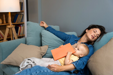Young mother fell asleep after reading fairy tale story book to her baby. Tired mommy sleeping with...