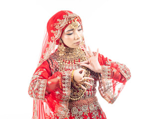 Close up portrait of a beautiful Asian Muslim lady in a hijab wearing a gorgeous Bollywood or Indian themed red traditional wedding dress isolated on white background