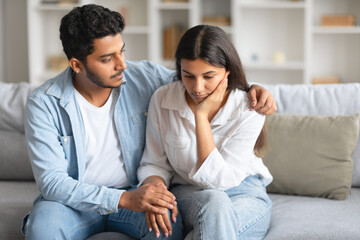 Caring indian husband soothing his distressed wife on sofa