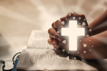 Christian Religion concept background. Hands folded in prayer on a Holy Bible with Christ's love...