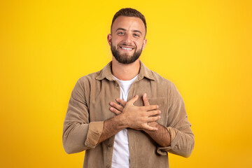 Happy handsome millennial european guy presses hands to chest