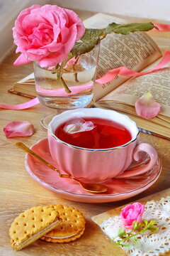 Still life with a pink cup with hibiscus tea and cookies