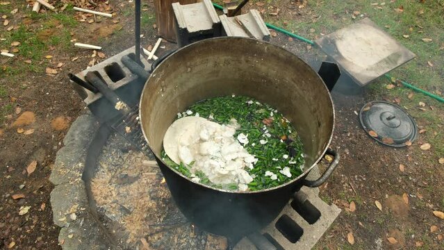 Cooking animal feed over fire pit using food craps mix with green beans ends and crumbled egg shells.