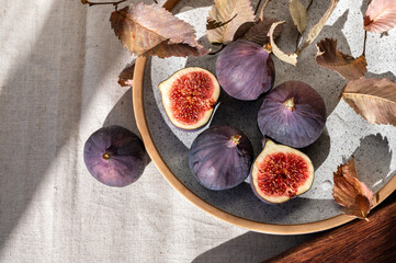 Whole and cut fig fruits on table, on neutral beige linen tablecloth background. Aesthetic...