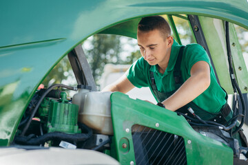Young mechanic repair tractor outdoor