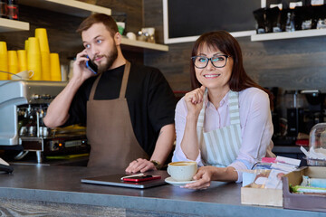 Team male and woman talking, working, using phone, coffee shop