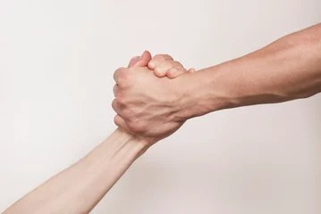 Fotobehang The concept of support and mutual understanding, helping one's neighbor, two hands holding each other, stronger hand holding the weaker one and helping in trouble © Мар'ян Філь