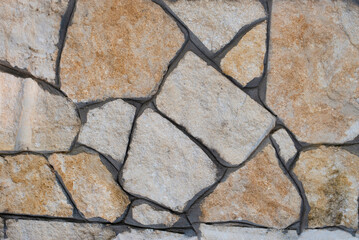 Part of a fence made of large unhewn stones, vintage old wall made of old stones, sand stone construction background