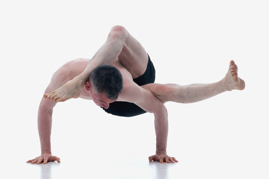 Eka pada sirsasana. (One Leg Behind the Head Pose), Ashtanga yoga  Man wearing sportswear doing Yoga exercise against white background.