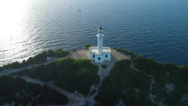Aerial drone view of the cliffs and the white lighthouse or Cape Ducato Lefkas at sunset in the southern area of Lefkada island, Greece.
