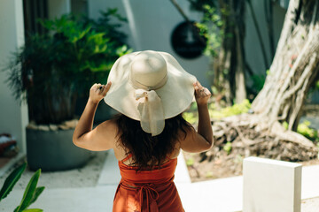 woman tourist in hat green leaves exotic hotel back view