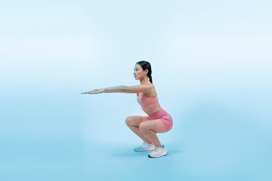 Vigorous energetic woman doing exercise. Young athletic asian woman strength and endurance training session as squat workout routine session. Full body studio shot on isolated background.