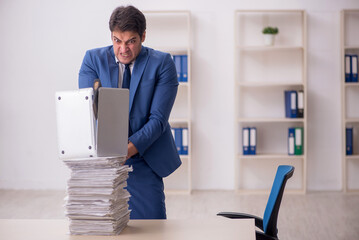 Young male employee unhappy with excessive work in the office