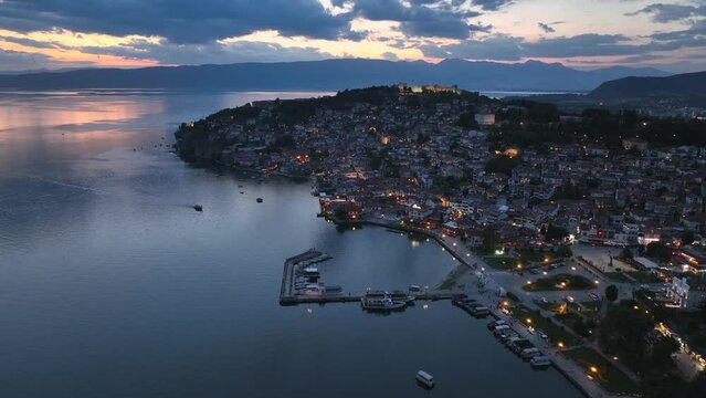 Aerial Twilight drone view of Ohrid City at Night in North Macedonia. Old Town on Ohrid lake with a beautiful fortress