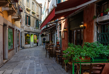 Old street with tables of restaurant in Venice, Italy. Architecture and landmark of Venice. Cozy cityscape of Venice.