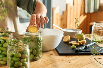 Woman preparing fermented olives in glass jar with slices of lemon, wild fennel and canning brine. Autumn vegetables canning. Healthy homemade food. Conservation of harvest.
