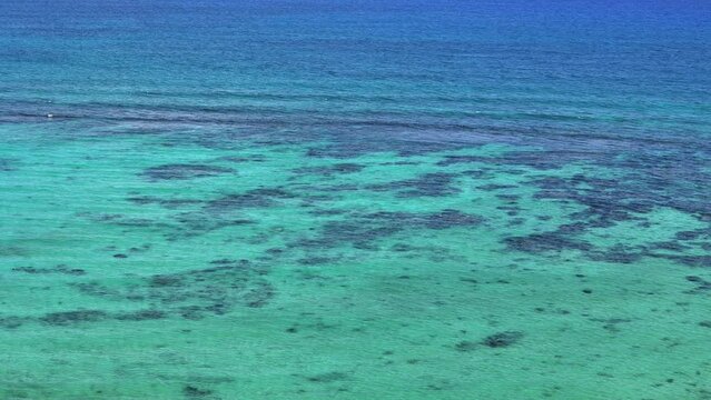 Close up of transparent blue Caribbean Sea with coral reef and small waves on a sunny day in Tulum