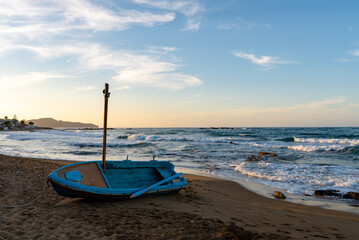 Old wooden blue boat on the beach during sunset. Agii Apostoli beach, Chania, Crete