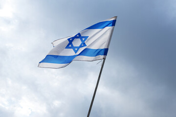 The flag of Israel on a field and a cloudy sky