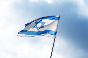 The flag of Israel on a field and a cloudy sky
