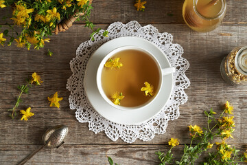 A cup of St. John's wort tea with Hypericum perforatum blossoms, top view