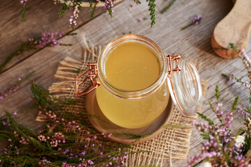 A jar of herbal syrup with fresh wild heather plant