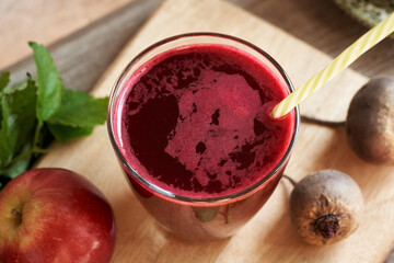 A glass of red beet juice with fresh apples and beetroot