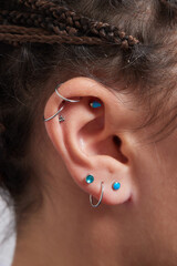 Professional placing the jewel of piercing on the temple on the head with ball. Tragus type.