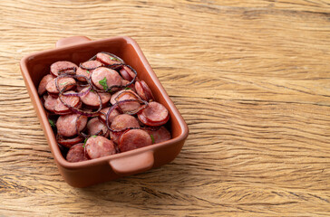 Grilled calabrese sausage portion with onion over wooden table with copy space