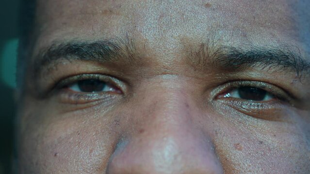 One black man becoming serious, macro close-up eyes of person changing emotion from happy to upset, extreme detail of eye staring at camera