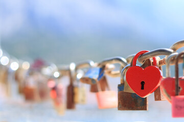 Love locks and hearts. Close-up of love lock with a red heart hanging on chain in on background of...