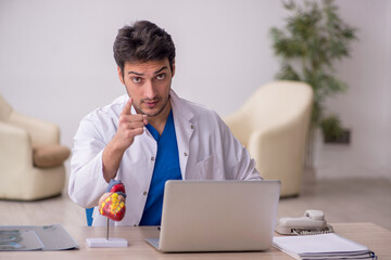 Young male doctor cardiologist sitting at the hospital