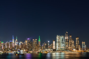 Aerial New York City skyline from New Jersey over the Hudson River with the skyscrapers of the Hudson Yards district at night. Manhattan, Midtown, NYC, USA. A vibrant business neighborhood