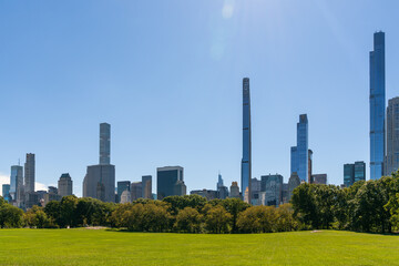 Fototapeta na wymiar Green lawn at Central Park and Manhattan skyline skyscrapers at day time, New York City, USA