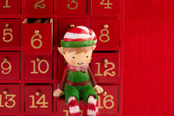 Christmas advent calendar with an elf and gifts on red background