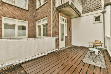 an outside area with wood flooring and white curtains on the side of a brick building that is being used as a balcony