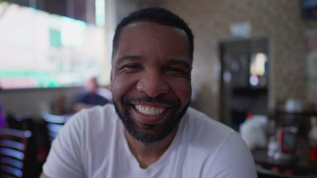 One happy black Brazilian Man smiling at camera inside traditional cafeteria restaurant. Close-up face of a joyful person portrait