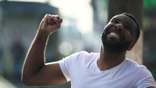 One joyful black Brazilian man celebrates success by thanking GOD in the air. Person having gratitude elated by positive news