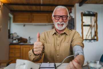 Man senior caucasian male use device to measure blood pressure at home