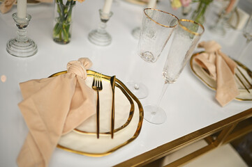 gold cutlery and napkin close-up on beautiful white plates at the event.