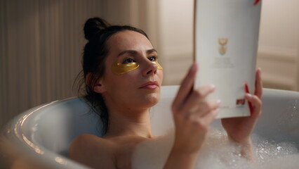 Chilling lady read novel enjoying spa procedures at bath. Woman laying bathroom