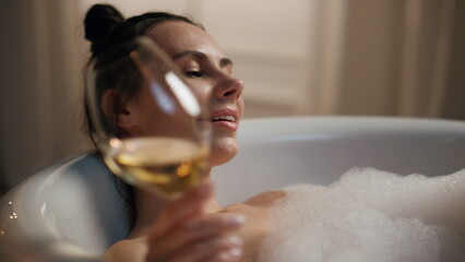 Carefree girl testing alcohol resting bathtub evening. Lazy woman enjoying spa