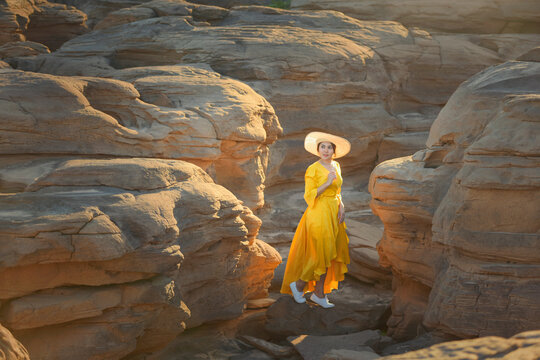 Woman in a yellow dress standing in canyon by Mekong River, Sam Pan Bok, Ubon Ratchathani, Thailand